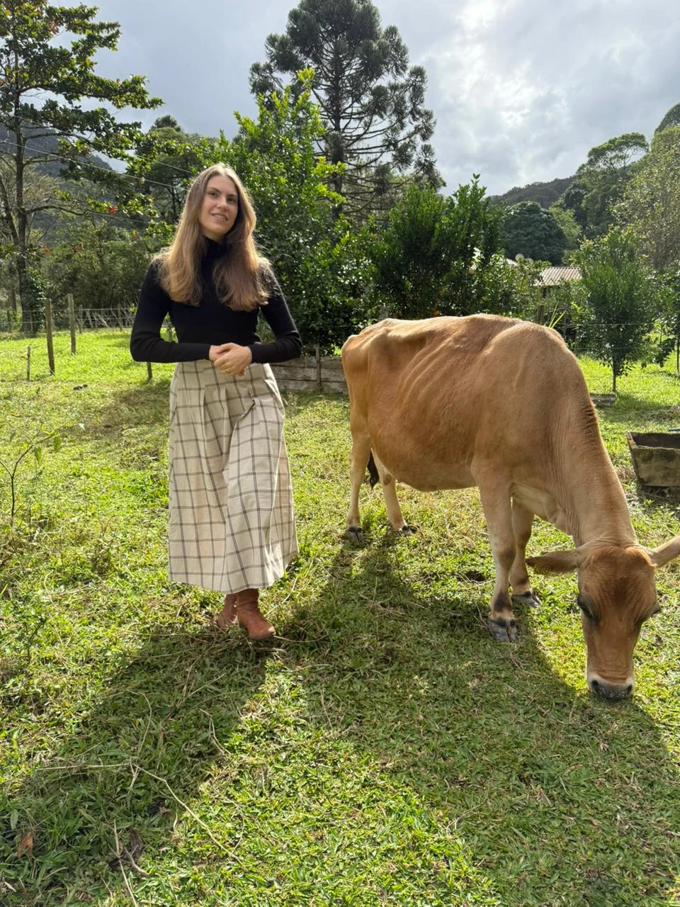 Carolina Pansera no campo, ao lado de uma vaca